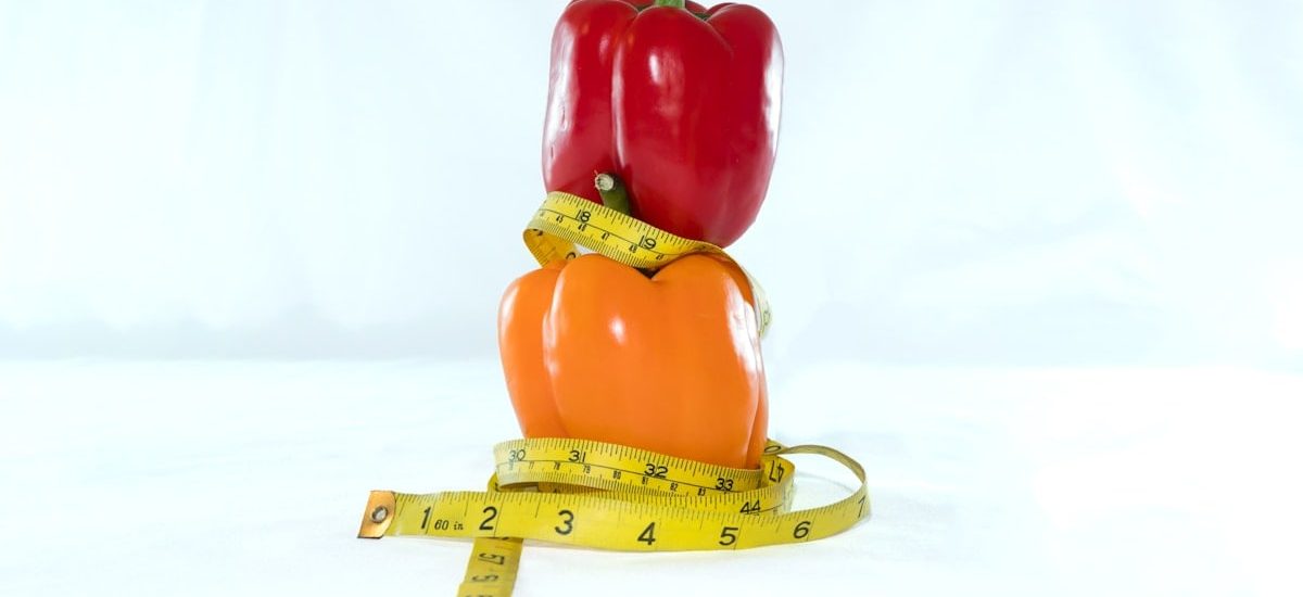 a red pepper sitting on top of a measuring tape