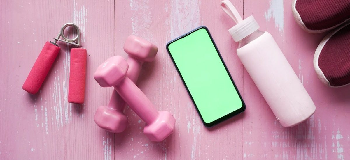 Smart phone with sports equipment on wooden floor.